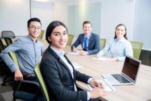 Diverse group of professionals in a meeting room discussing staffing solutions for seasonal employment in Wisconsin, with a laptop on the table.
